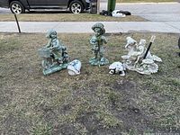 View showing all lawn ornaments arranged on grass: girl on bike with cat, boy with puppy, frog shell sculpture, and turtle figurine.