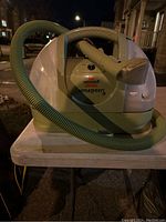 Front view of Bissell Little Green upholstery cleaner showing hose, handle, and Bissell branding.
