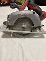 Side view of Milwaukee circular saw showing the blade guard, handle, and brand logo.