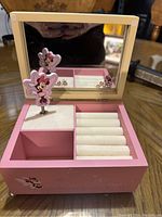 Open pink wooden jewellery box with mirror and Minnie Mouse ring holder inside.