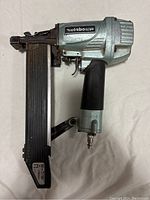 Side view of the Metabo HPT pneumatic nailer showing the metal magazine for nails, ergonomic grip, and trigger mechanism.