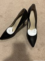 View of both black Nine West women's heels showing pointed toes and beige inner lining. Shoes stuffed with paper to retain shape.