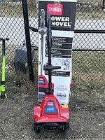Photo of the Toro Power Shovel in red with its original box behind, showing the full item and packaging for clear identification.
