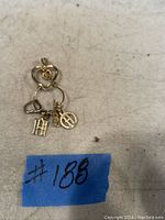 Three 10K gold pendants displayed on neutral surface: solid heart, open heart and multi-charm ring pendant.