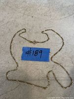 Full view of 14K gold chain necklace laid out flat next to blue label showing #189