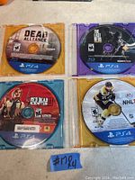Photo of four PS4 game discs: Dead Alliance, The Last of Us Remastered, Red Dead Redemption II, NHL 17. All discs appear in good condition.