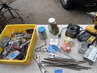 Wide shot showing most tools including cordless drill, charger, wrench, files, and tub of smaller tools and hardware.