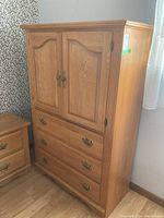 Front view of the oak chest showing two doors and three drawers with brass hardware.
