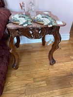 Marble topped side table shown from front with two decorative items on top and visible carved legs.
