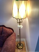 Full view of the vintage floor lamp placed next to a couch, showing the lamp lit to highlight shade and lamp height.