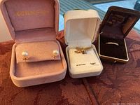 Photo showing the pearl earrings in a pink Kerbs box, the 10K gold eagle pendant in its box, and a diamond ring in a brown F.B. Phillips & Son box