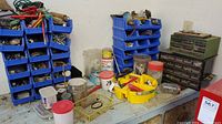 Overview of workbench surface with multiple blue plastic organizers filled with small hardware items, assorted hand tools and small containers
