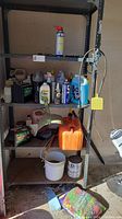 Photo of metal shelving unit with various automotive and cleaning supplies including batteries, Jerry can, and WD-40 spray