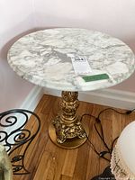 Front view showing round marble top and gold-tone pedestal base