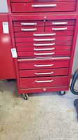 Front view of red steel tool chest showing drawers and casters