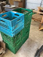Six plastic milk crates stacked (four green, two blue). Photo shows the crates' lattice sides and open handles.