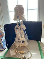 Full view of the porcelain lamp with base showing the couple and dog figurine, power cord and porcelain shade with floral pattern.