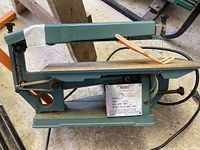 Side view of the scroll saw showing full body, table surface, motor, and nameplate.