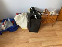 Wide view showing the sewing box, multiple bags of supplies including thread, buttons, and tools on the floor.
