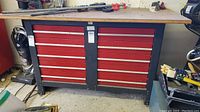 Front view of full Sears tool bench showing 10 red drawers in 2 columns with silver handles and black metal frame with wooden top.