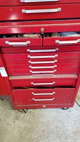 Red multi-drawer tool cabinet containing various tools and supplies.