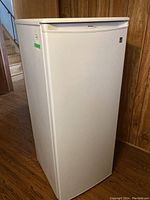 Front and side view of white upright freezer showing full unit appearance.
