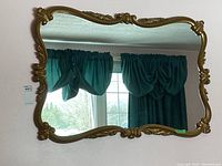 Front view of the large wall mirror showing the full reflective surface and decorative gold frame edges with scroll designs.