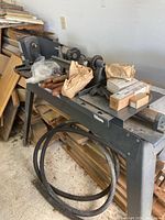 Full view of lathe on stand with assorted accessories on bed and belt looped below