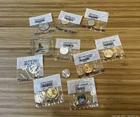 Overhead view of eight sealed coin sleeves laid out on wood surface alongside a small metal eagle piece