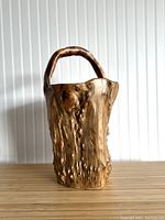 Front view of a large vintage hand carved burl wood basket with handle.
