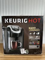 Front view of the Keurig Hot K600 Series coffee maker box showing the features including 80oz water reservoir and compatibility with ground coffee and pods.