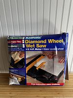 Image showing original packaging box with brand name Plasplugs and description of wet saw with diamond wheel and 1/2 H.P. motor.