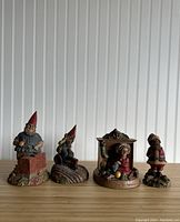 Front view of all four figurines showing their size and details with white beadboard background and wooden surface