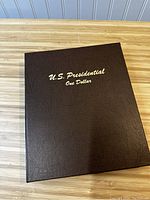 Brown textured cover of the collection book titled 'U.S. Presidential One Dollar'