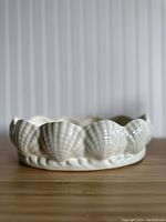 Front view of vintage white ceramic bowl showing detailed seashell rim design and glossy finish.