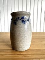 Front view of the glazed stoneware vase showing beige base color with blue floral decoration.