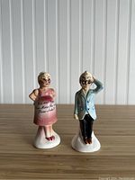 Front view of Enesco pregnant couple salt shakers showing the woman's pink dress with text and man in blue jacket