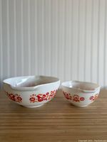 Front view of the two nesting bowls showing the red and orange Friendship pattern of birds and flowers.