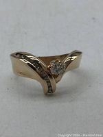 Front angle showing six-prong set center diamond and channel set side diamonds