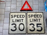 View of both speed limit signs (30 and 35) alongside the red reflective warning triangle against a tiled floor showing the lot contents.