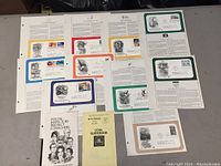 Group photo showing nine 3-hole punched collection pages with commemorative covers and two booklets arranged on a surface.