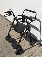 Front angle view of Dynarex DynaGo Duo Transport Rollator with seat, hand brakes, and footrests visible.