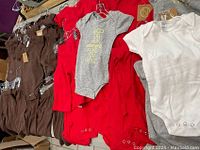 Collection of toddler baby bodysuits in brown, red, gray, and white colors showing different angles and quantity