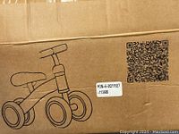 Cardboard box with printed illustration of the balance bike showing seat, two front wheels, and handlebar.