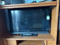 Sony 40-inch flatscreen TV on wooden shelf with remote control in front.