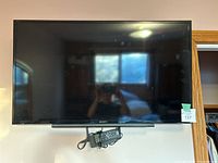 Mounted Sony flat screen TV on wall with remote control and power adapter under it