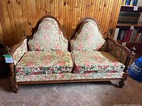 Front view of vintage 2-seat chesterfield love seat with floral tapestry upholstery and wood frame.