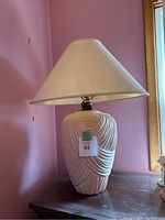 Full view of the vintage lamp showing the light pink ceramic base with textured Art Deco styling and cream-colored shade.