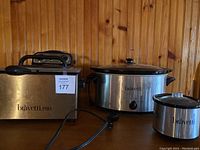 Photo of three Bravetti kitchen appliances including deep fryer, crockpot, and mini warmer on wooden surface.
