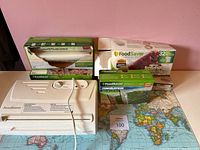 FoodSaver vacuum sealer and multiple boxes of vacuum storage bags arranged on a map surface.